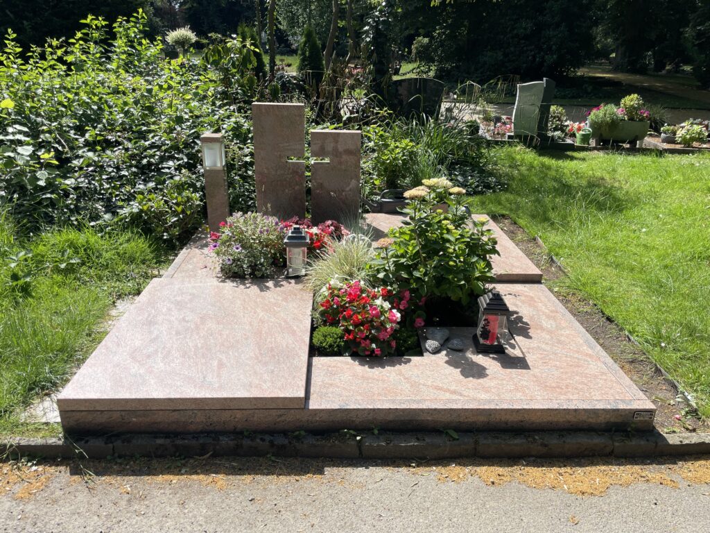 Doppelgrabanlage aus rotem Granit mit Kreuz-Aussparung und Bepflanzung